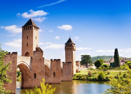 The Pont Valentré, a fortified stone arch bridge from the 14th century, spans six arches over the Lot River, situated to Cahors